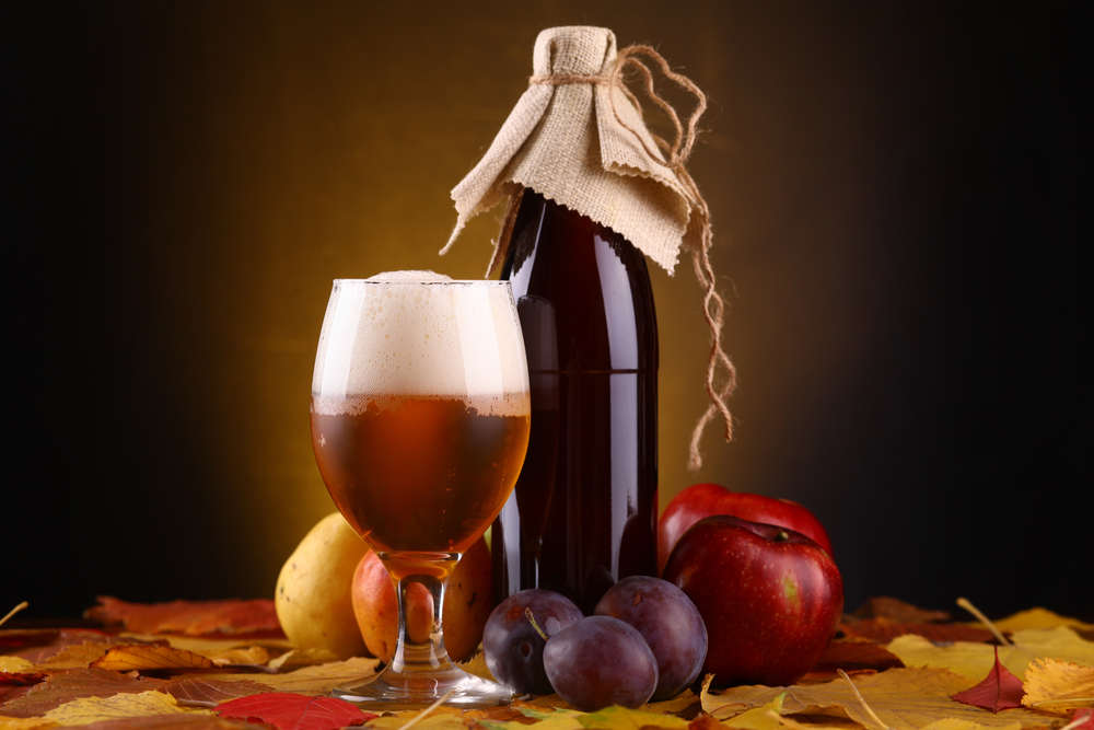 Bottle and glass of beer surrounded by fruit
