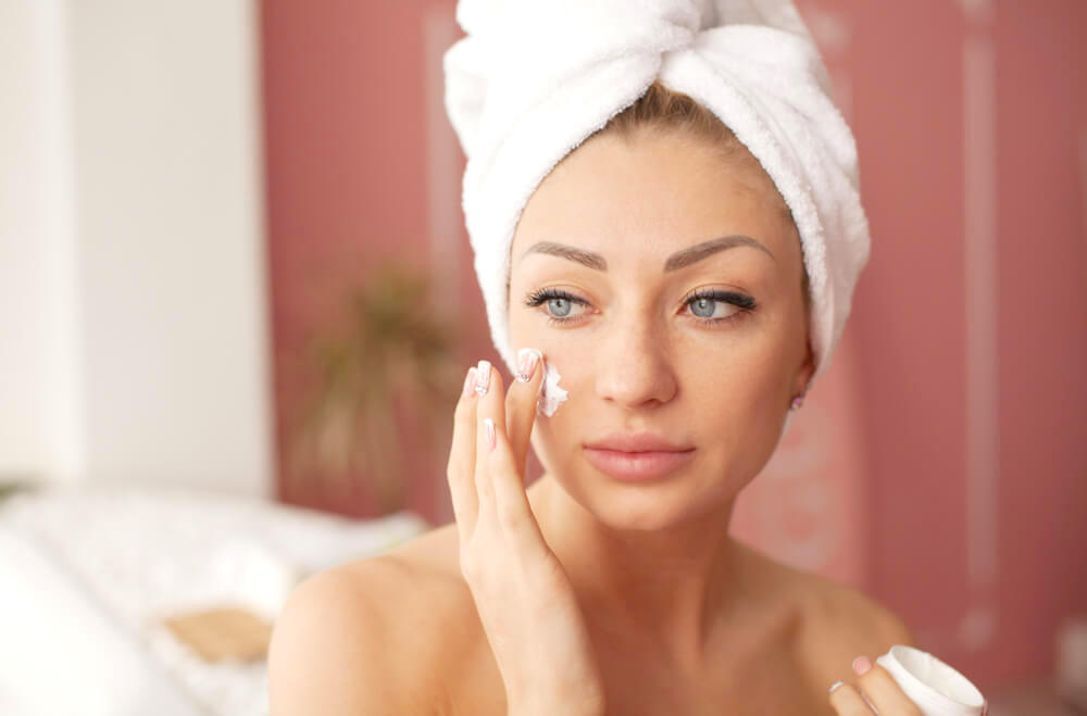 Woman applying moisturiser to face