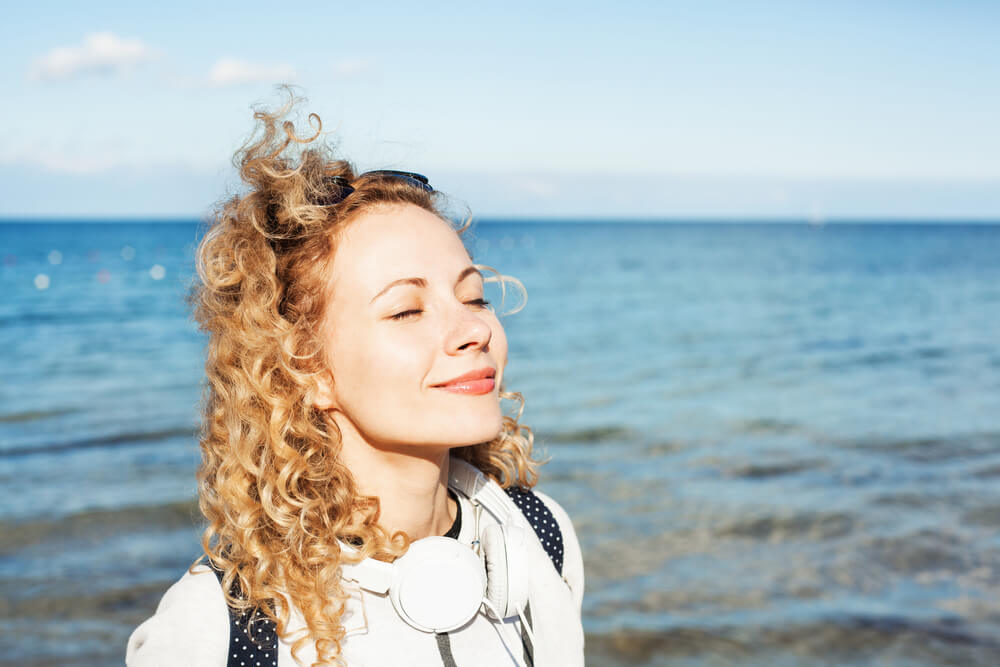 Smiling woman breathing deeply in front of ocean