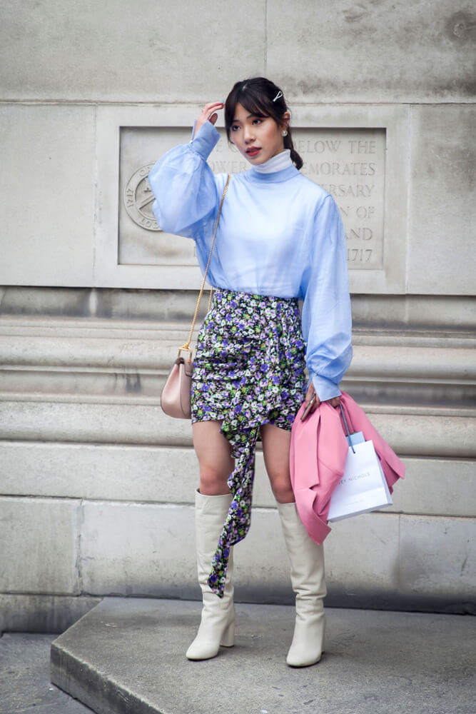 LONDON - FEBRUARY 15, 2019: Stylish attendees gathering outside 180 The Strand for London Fashion Week. A girl in a blue chiffon blouse, a colorful skirt in flowers and a pink jacket