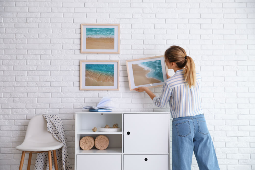 Woman hanging paintings on wall