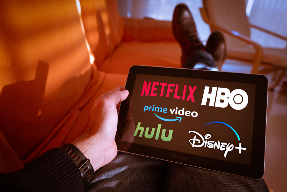 Holding tablet with streaming TV networks showing