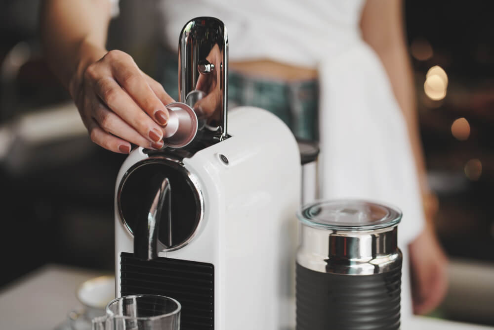 Woman placing capsule into coffee machine