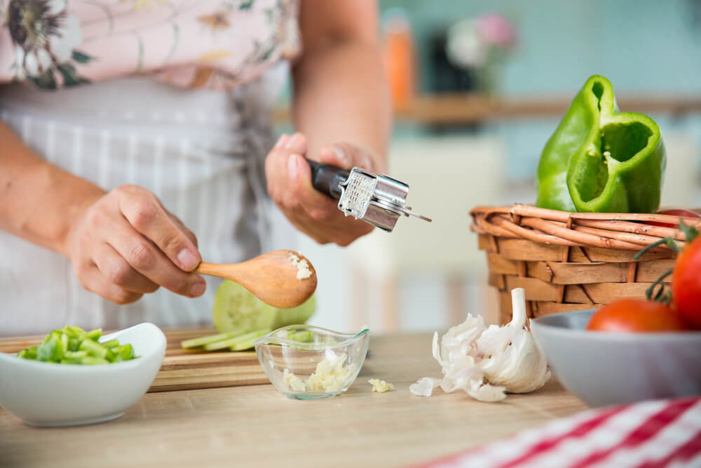 Woman cutting garlic in kitchen