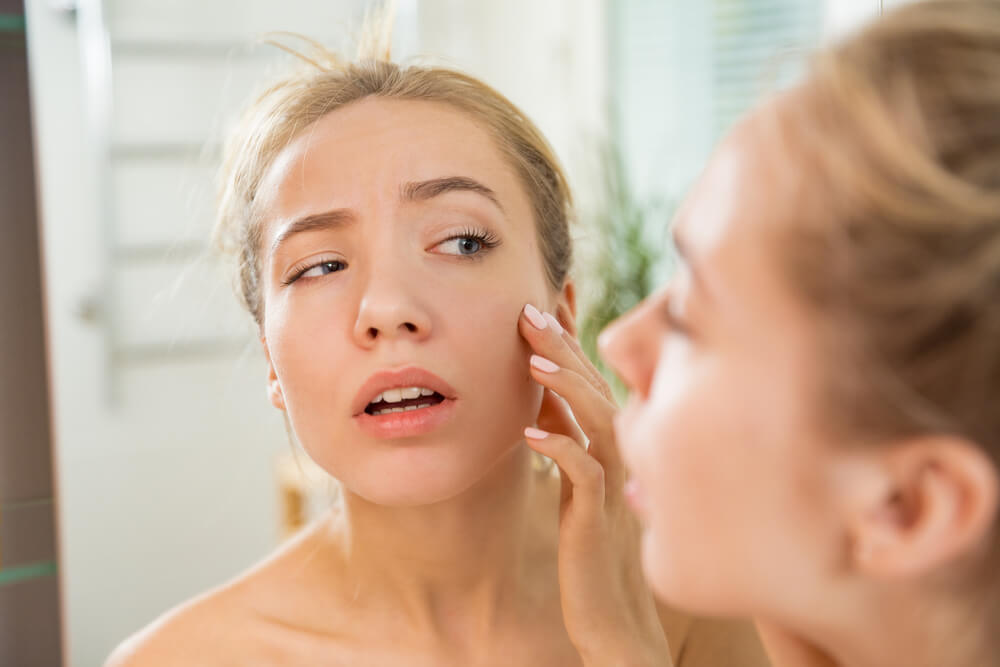 Woman pointing at face in mirror
