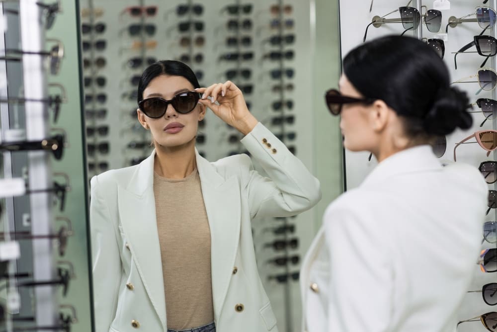 Woman wearing quiet luxury clothes trying on sunglasses